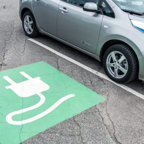 Grønt felt for elbilparkering, og en grå elbil