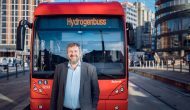 Bernt Reitan Jenssen i Ruter står foran en av de røde hydrogenbussene i Oslo sentrum.