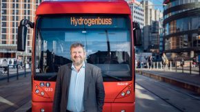 Bernt Reitan Jenssen i Ruter står foran en av de røde hydrogenbussene i Oslo sentrum.