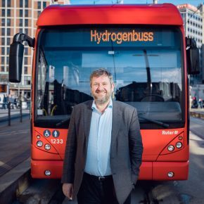 Bernt Reitan Jenssen i Ruter står foran en av de røde hydrogenbussene i Oslo sentrum.