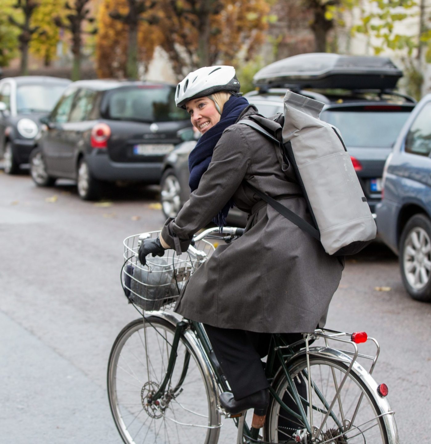 Mari Synnevåg på sykkelen. Sykler forbi rekken med biler som står parkert langs veien.