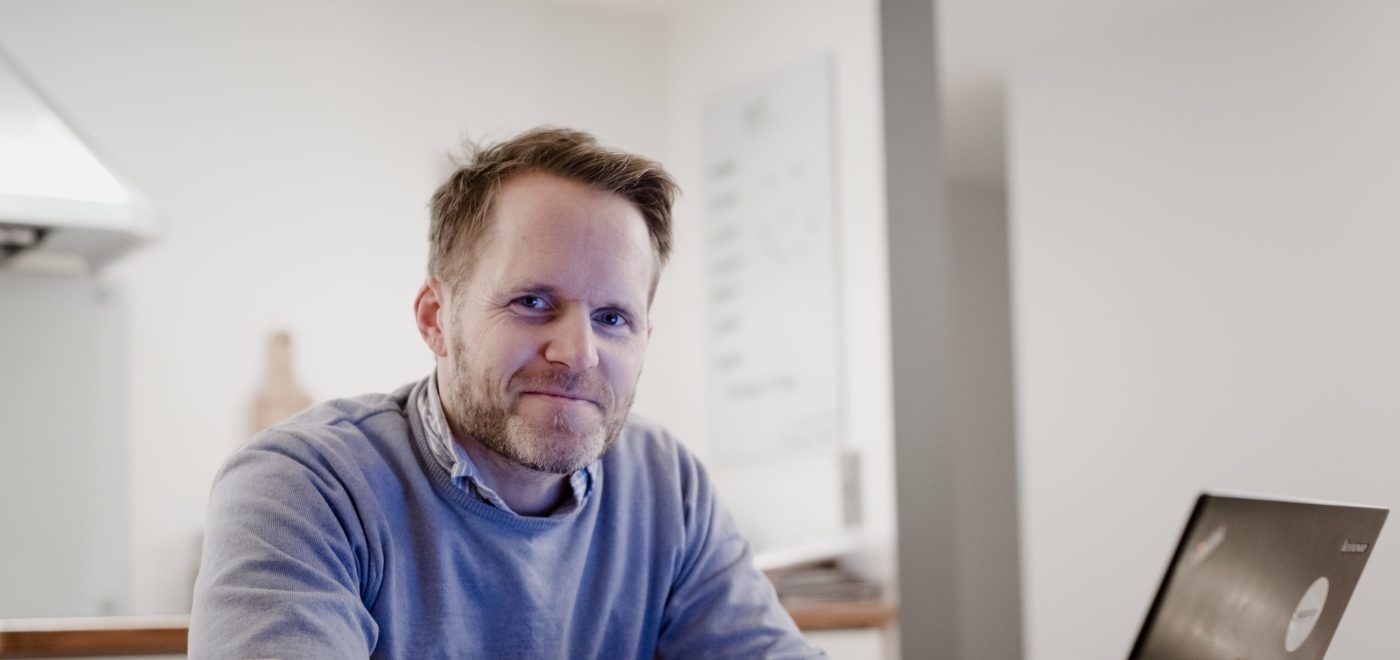 Kjell Havre Iversen sitter foran en bærbarpc på kjøkkenbordet og søker på energiportalen.no