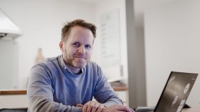 Kjell Havre Iversen sitter foran en bærbarpc på kjøkkenbordet og søker på energiportalen.no