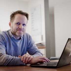 Kjell Havre Iversen sitter foran en bærbarpc på kjøkkenbordet og søker på energiportalen.no