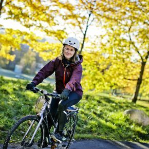 Torunn Brånå sykler på foran trær på Sagene.