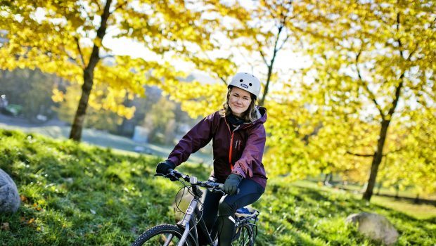 Torunn Brånå sykler på foran trær på Sagene.