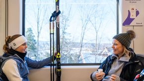 Jente og kvinne sitter på t-banen med ski