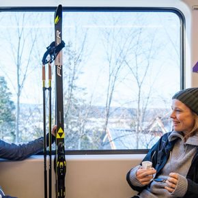 Jente og kvinne sitter på t-banen med ski