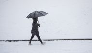 En person som går med paraply. Snø på bakken