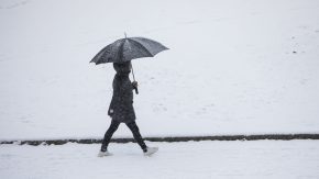 En person som går med paraply. Snø på bakken