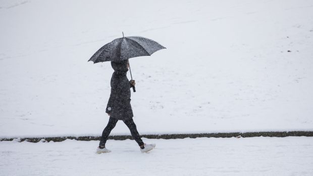 En person som går med paraply. Snø på bakken