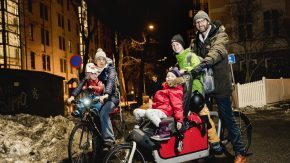 En familie på to sykler. En ellastesykkel som er lastet med både barn og ryggsekker.