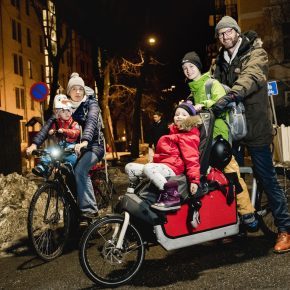 En familie på to sykler. En ellastesykkel som er lastet med både barn og ryggsekker.