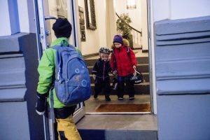Three children on their way out of the front door of an apartment in Vika.