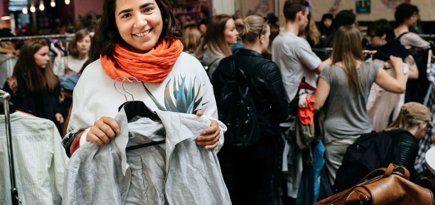 Sofia Langthaler holder fram en grå jakke som hun har byttet under klesbyttedagen. I bakgrunn er en stor folkemengde som er på klesbyttedagen.