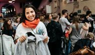 Sofia Langthaler holder fram en grå jakke som hun har byttet under klesbyttedagen. I bakgrunn er en stor folkemengde som er på klesbyttedagen.