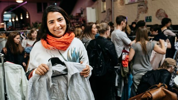 Sofia Langthaler holder fram en grå jakke som hun har byttet under klesbyttedagen. I bakgrunn er en stor folkemengde som er på klesbyttedagen.