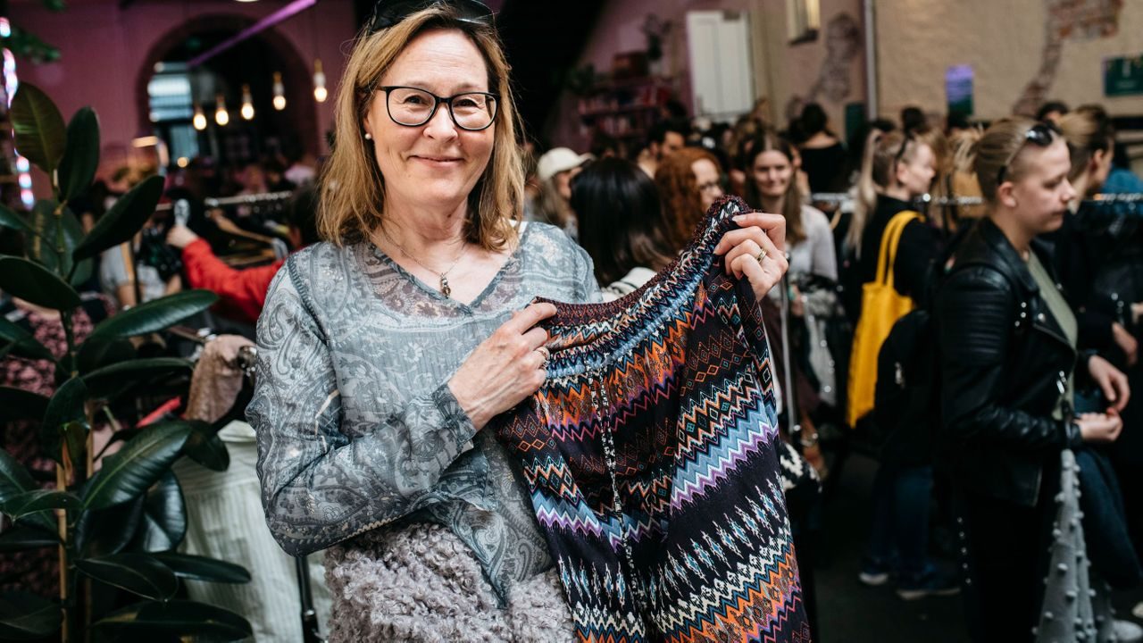 Tanja Aarsand holder fram en genser hun bytter til seg på Klesbyttedagen