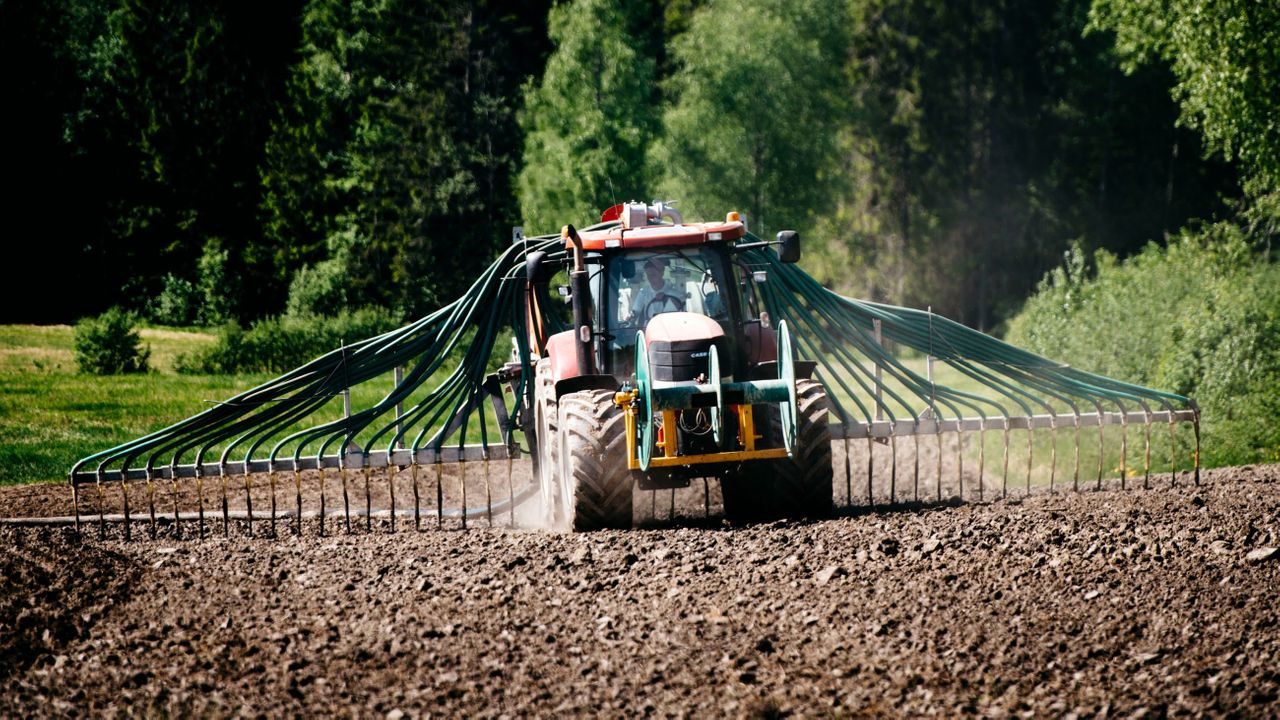 Traktor på jorde sprer gjødsel fra Oslos matavfall