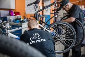 En mann med ryggen til reparerer en sykkel