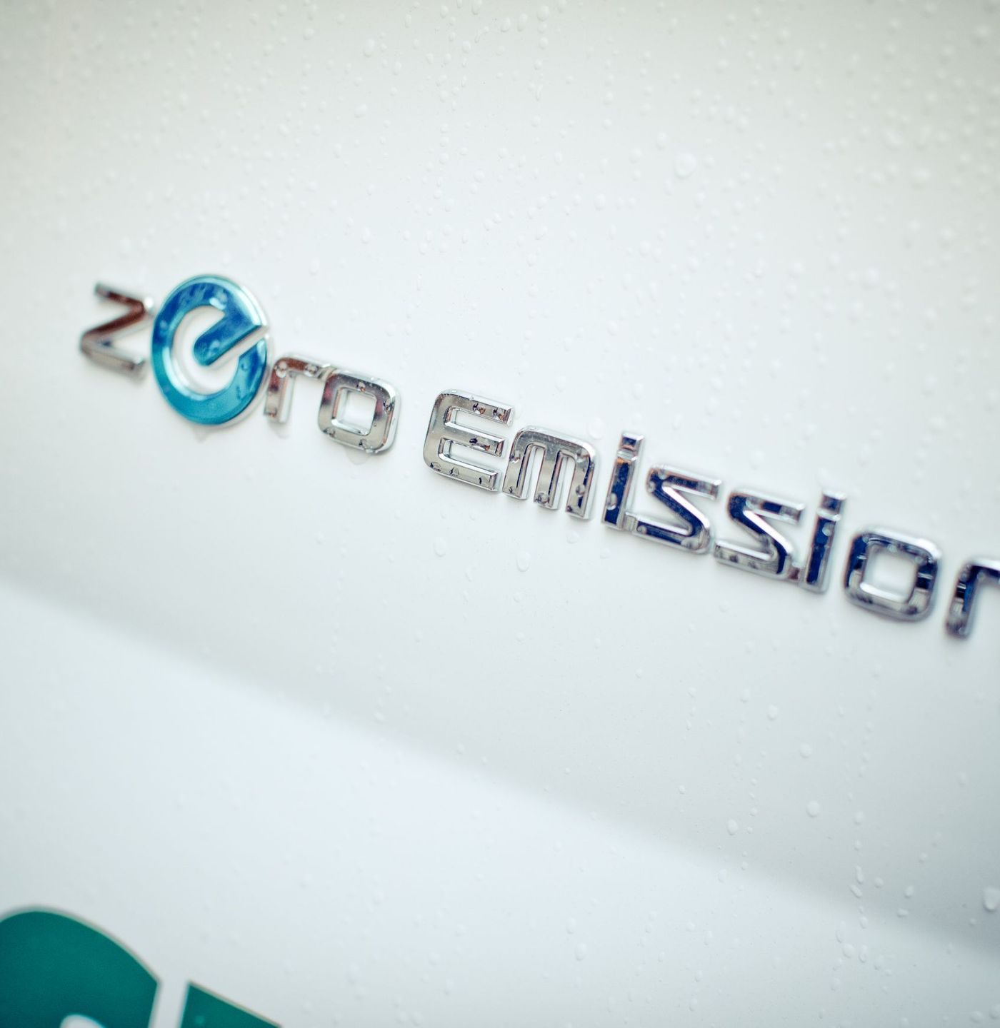 Zero emission skrevet i sølvbokstaver på en hvit bil, nærbilde.