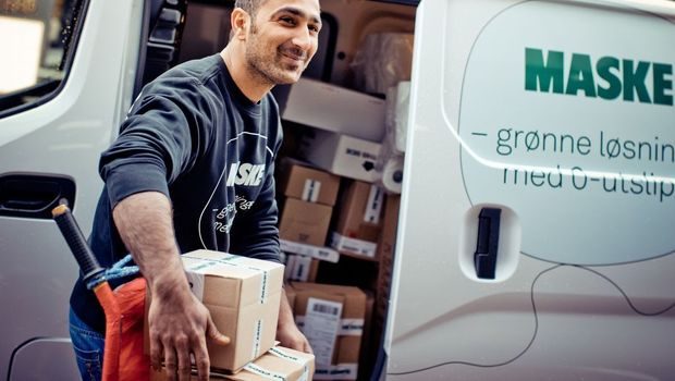 Mann som bærer en pappeske ut av en åpen elvarebil