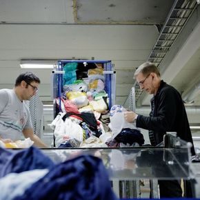 To menn sorterer klær som er levert til Fretex