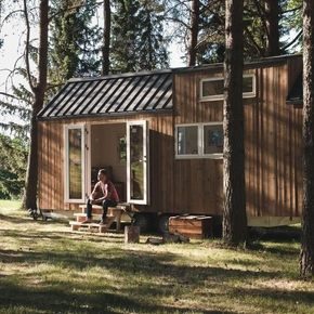 Mann sitter på trappen foran mikrohus i skogen