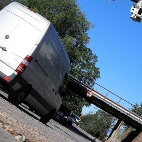 Skrått bilde av en elvarebil som kjører gjennom en bomstasjon i Oslo. Blå himmel.