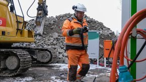 Mann med ladekabel ved ladekontainer