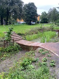 En forsenkning i bakken hvor overvannet kan samle seg og en bro som går over slik at folk kan krysse den.